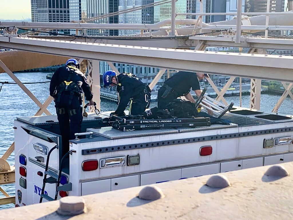 Members of NYPD’s Emergency Services Unit stow their tactical ladders following the successful rescue of a Brooklyn Bridge climber on Friday. Photo: Mary Frost, Brooklyn Eagle