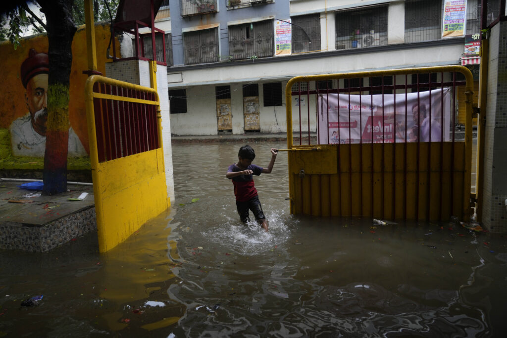 A boy plays in the flooded water at an entrance door after heavy rains in Mumbai, India, Monday, July 8, 2024. (AP Photo/Rafiq Maqbool)