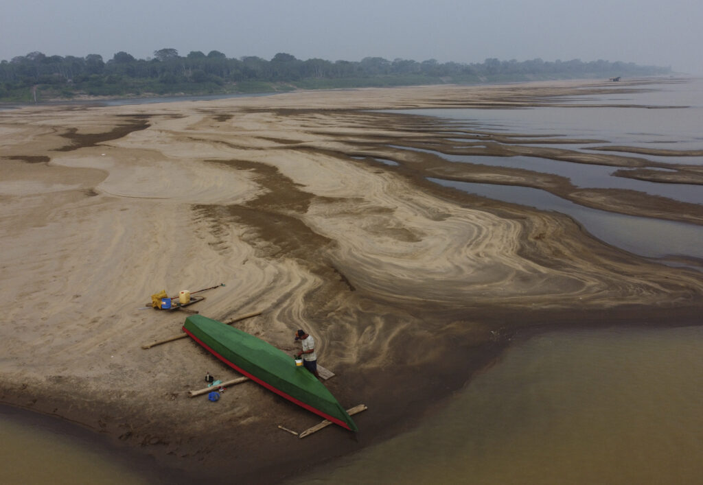 Reis Santo Vieira paints a boat on a dry part of the Madeira River, a tributary of the Amazon River, during the dry season in Humaita, Amazonas state, Brazil, Saturday, Sept. 7, 2024. (AP Photo/Edmar Barros)