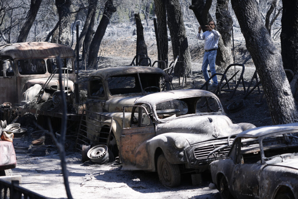 A reporter takes cell phone images of the devastation left behind by the Airport Fire, Wednesday, Sept. 11, 2024, in El Cariso Village, in unincorporated Riverside County, Calif. (AP Photo/Gregory Bull)