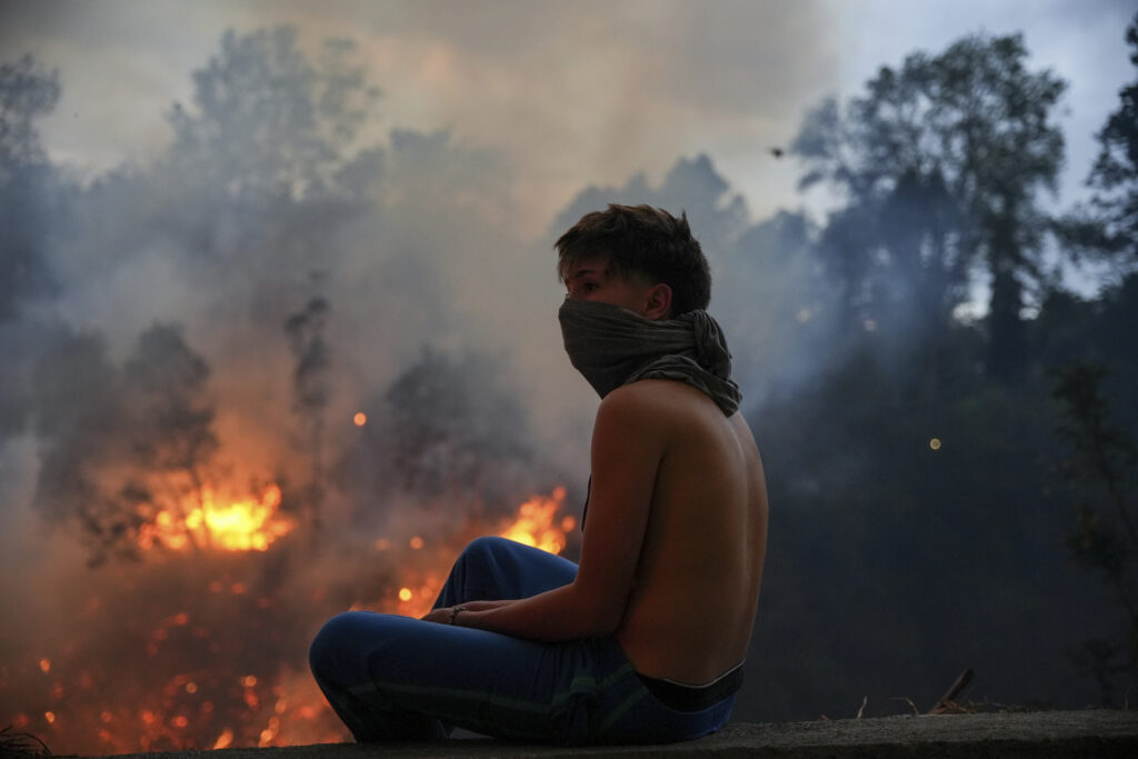 A resident watches fires burning in a forested area in the Guapulo neighborhood of Quito, Ecuador, Tuesday, Sept. 24, 2024. (AP Photo/Carlos Noriega)