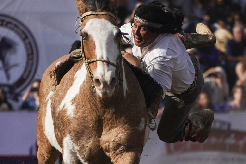 A man wearing traditional clothing performs acrobatics on a horse during Independence Day celebrations in Santiago, Chile, Tuesday, Sept. 17, 2024. (AP Photo/Matias Basualdo)