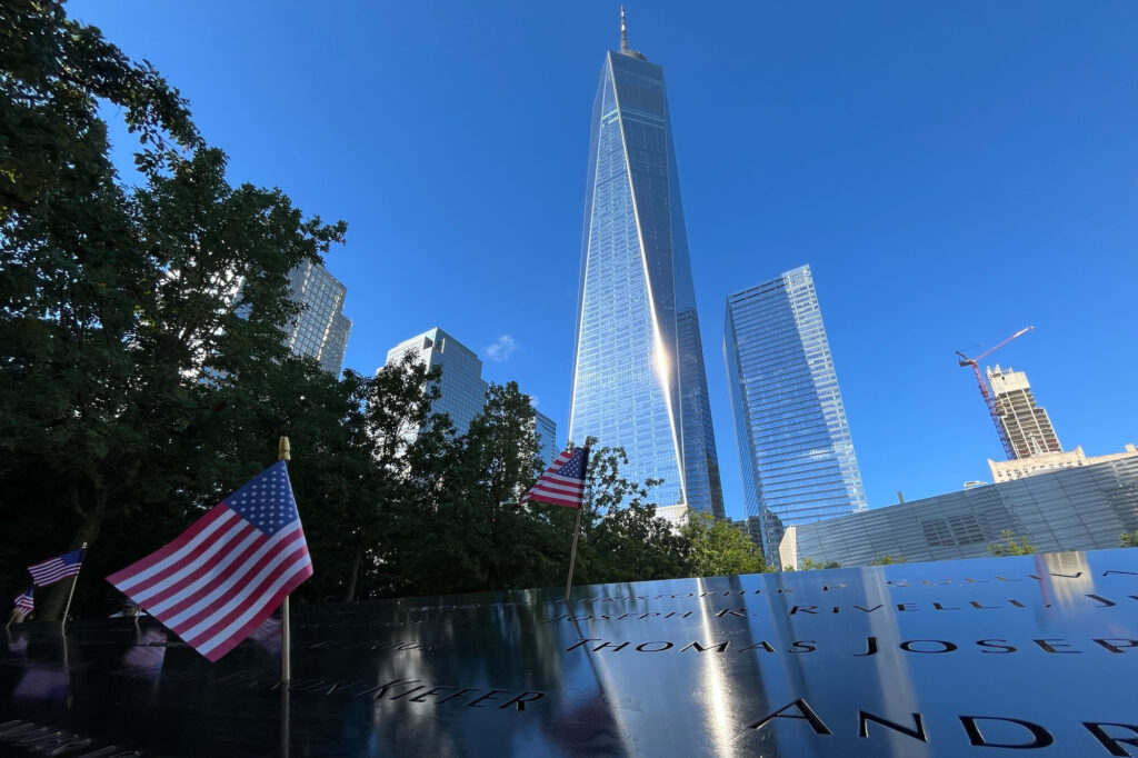 Flags are placed by the names of those killed during the Sept. 11, 2001, attacks at the reflecting pools at the National September 11 Memorial & Museum, Tuesday, Sept. 10, 2024, in New York. One World Trade Center rises in the background. AP Photo/Donald King