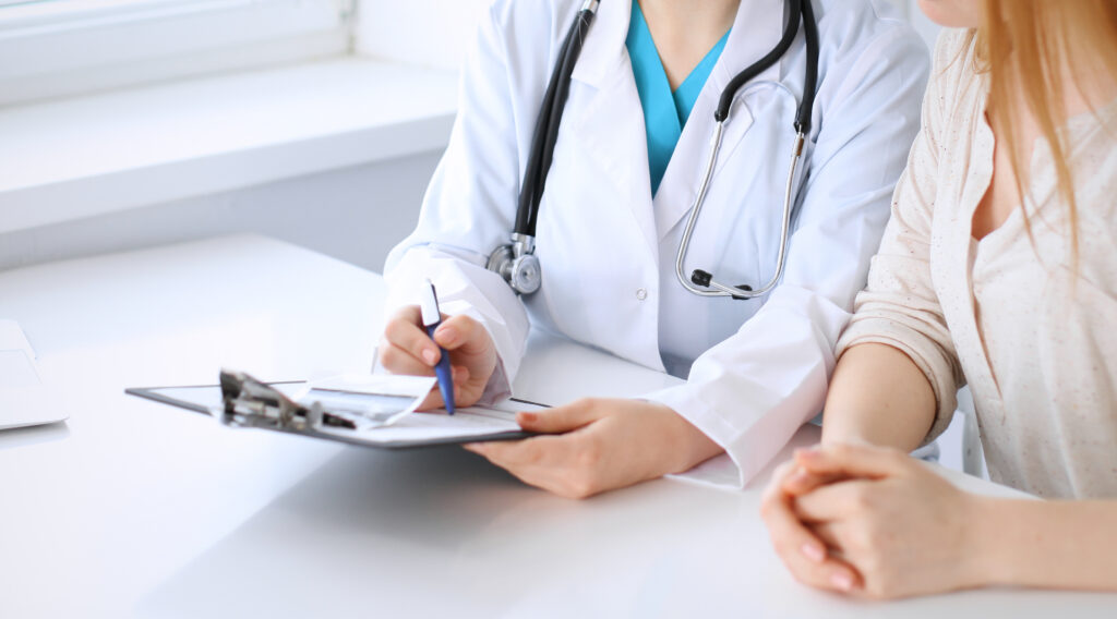 A doctor sits with a patient. Photo: rogerphoto/Adobe Stock