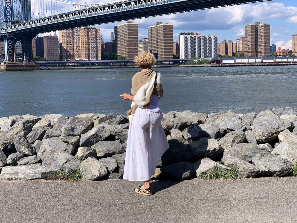 A woman, cigarette in hand, stands near the rocks where multiple human bones have been found in Brooklyn Bridge Park. Photo: Mary Frost, Brooklyn Eagle