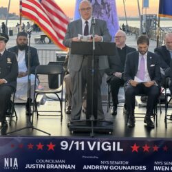 Councilmember Justin Brannan addressed the crowd from the podium. Seated, from left: Captain Kristen Schafer, State Sen. Andrew Gounardes and State Sen. Iwen Chu. Photo by Wayne Daren Schneiderman