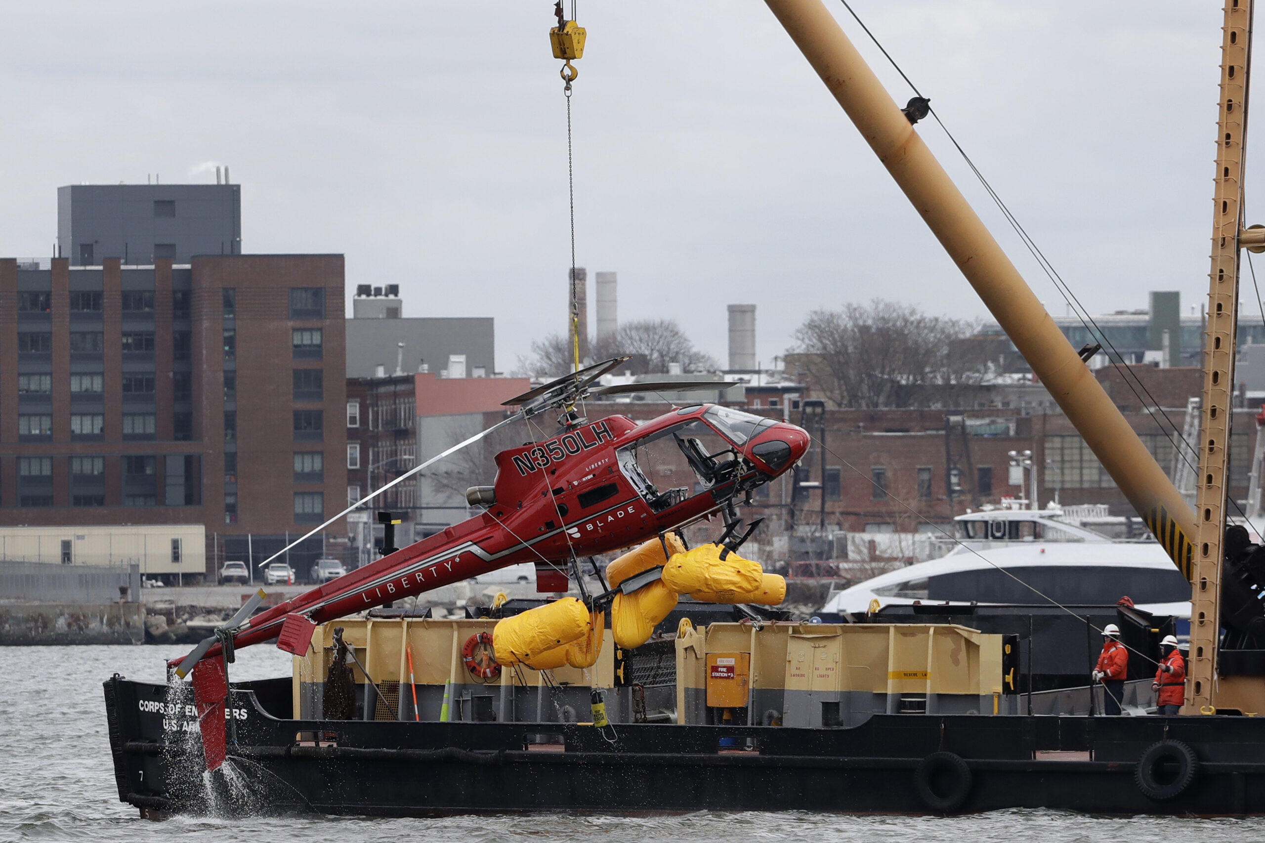 The helicopter in question is hoisted by crane from the East River onto a barge in New York on March 12, 2018. Photo: Mark Lennihan/AP