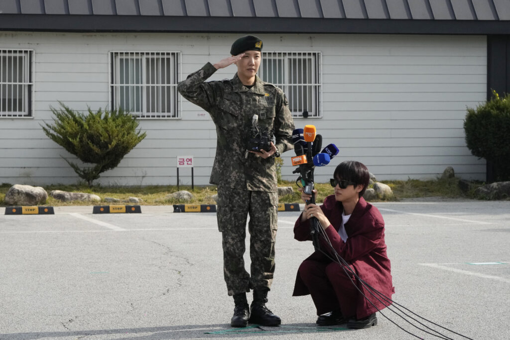 K-pop band BTS member J-Hope, center, salutes as fellow member Jin holds microphones after being discharged from a mandatory military service outside of an army base in Wonju, South Korea, Thursday, Oct. 17, 2024. (AP Photo/Ahn Young-joon)