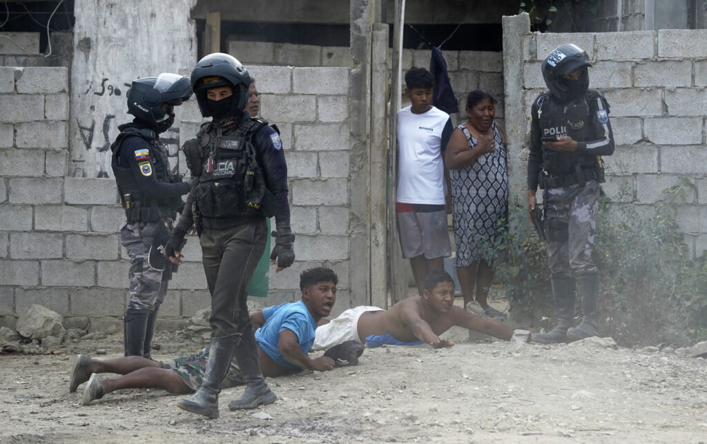 Residents lie on the ground as military and police officers raid a home as part of a joint operation searching for weapons and drugs in a neighborhood of Guayaquil, Ecuador, Wednesday, Oct. 16, 2024. (AP Photo/Cesar Munoz)