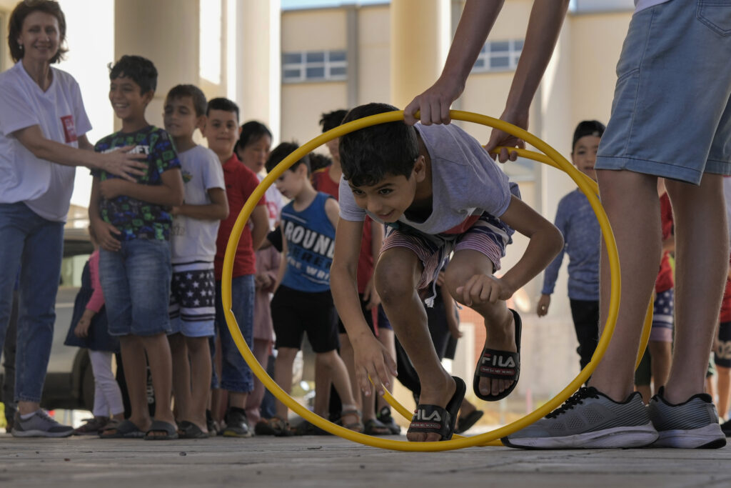 A volunteer of the Russian Cultural Center entertains displaced children at a school in Beirut, Lebanon, Thursday, Oct. 3, 2024, after fleeing the Israeli airstrikes in the south. (AP Photo/Bilal Hussein)