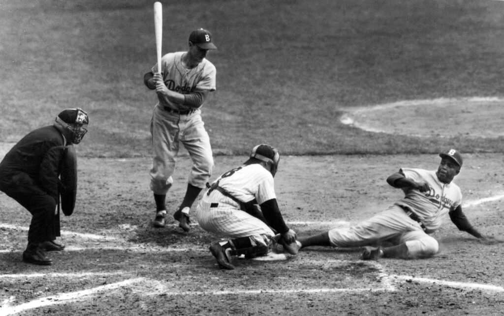 Brooklyn Dodgers' Jackie Robinson safely steals home plate under the tag of New York Yankees catcher Yogi Berra as pinch-hitter Frank Kellert looks on in the eighth inning of the World Series opener at New York's Yankee Stadium, Sept. 28, 1955. AP Photo/John Rooney, File