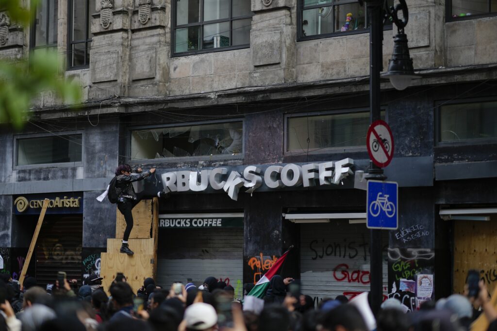 A demonstrator attacks a storefront on the 56th anniversary of the killing of student protesters at Tlatelolco plaza when soldiers opened fire on a peaceful demonstration, in Mexico City, Wednesday, Oct. 2. 2024. (AP Photo/Eduardo Verdugo)