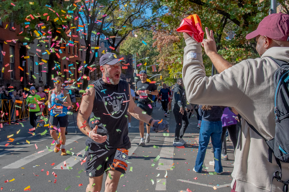 Define Run Club set off a confetti cannon as one of their members found them on the marathon race course on Sunday, Nov. 3, 2024. Photo by Beth Eisgrau-Heller