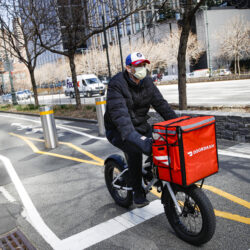 A delivery worker rides his bicycle along a path on the West Side Highway in New York, March 16, 2020. AP Photo/John Minchillo, File