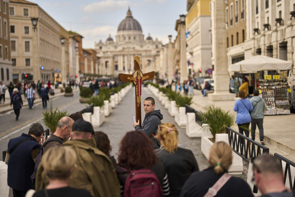 Worshippers pray as they walk towards St. Peter's Basilica, background, in Rome, Italy, Friday, March 7, 2025.