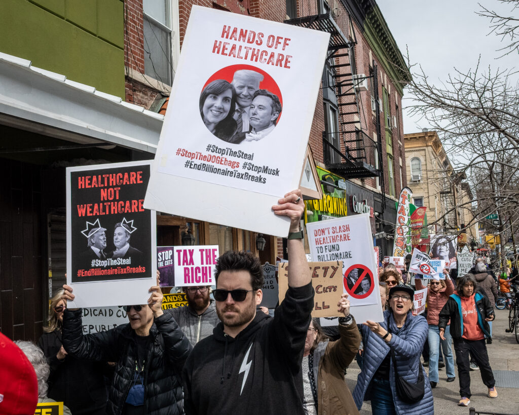A coalition of progressive organizations and unions — including Indivisible Brooklyn and 1199 SEIU United Healthcare Workers East — march to the Bay Ridge office of Congresswoman Nicole Malliotakis (R-Brooklyn) in Brooklyn, New York, March 22, 2025, protesting her vote to cut funding for federal health care programs and give tax breaks to billionaires. Brooklyn Eagle photo by Gabriele Holtermann