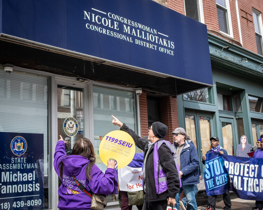 A coalition of progressive organizations and unions — including Indivisible Brooklyn and 1199 SEIU United Healthcare Workers East — rally outside the Bay Ridge office of Congresswoman Nicole Malliotakis (R-Brooklyn), in Brooklyn, New York, March 22, 2025, protesting her vote to cut funding for federal health care programs and give tax breaks to billionaires. Brooklyn Eagle photo by Gabriele Holtermann