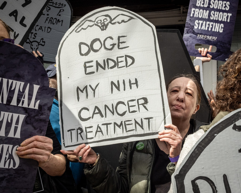 A coalition of progressive organizations and unions — including Indivisible Brooklyn and 1199 SEIU United Healthcare Workers East — rally outside the Bay Ridge office of Congresswoman Nicole Malliotakis (R-Brooklyn), in Brooklyn, New York, March 22, 2025, protesting her vote to cut funding for federal health care programs and give tax breaks to billionaires. Brooklyn Eagle photo by Gabriele Holtermann