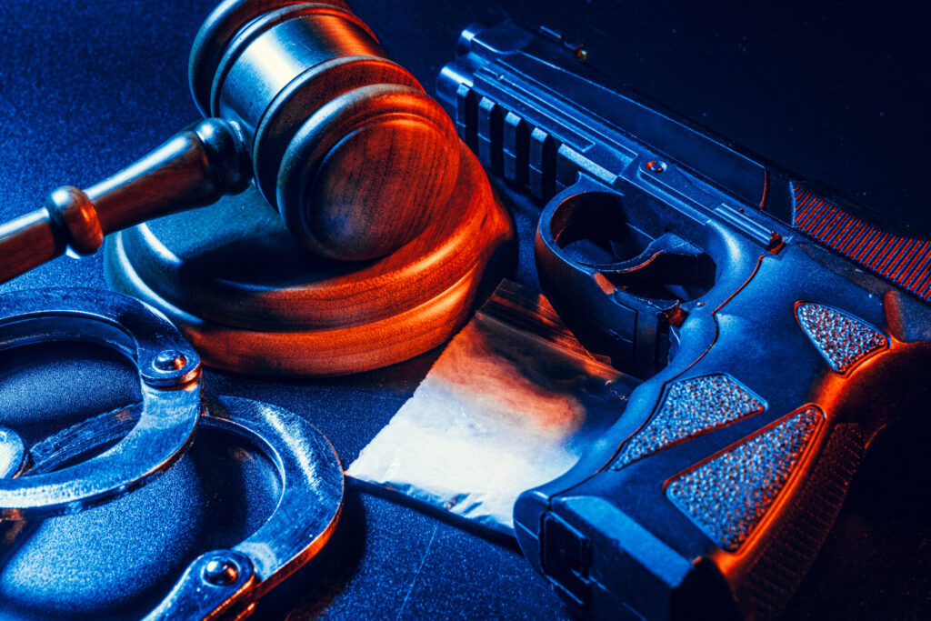 Judge gavel, handcuffs with white powder bag on dark table. Crime, robbery, drug trafficking concept cocaine, gun
