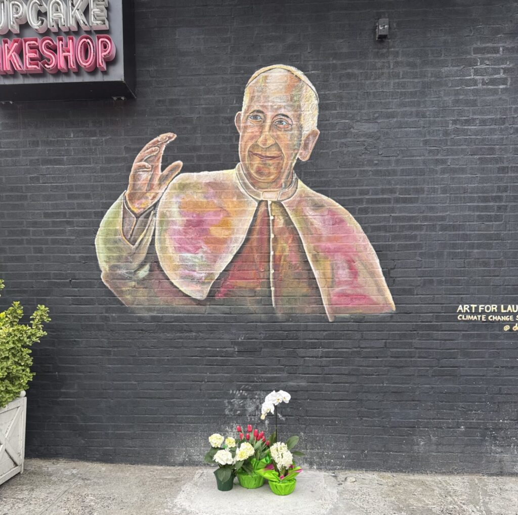 The mural of Pope Francis in Bay Ridge now has flowers underneath it. Photo courtesy of Delphinoto