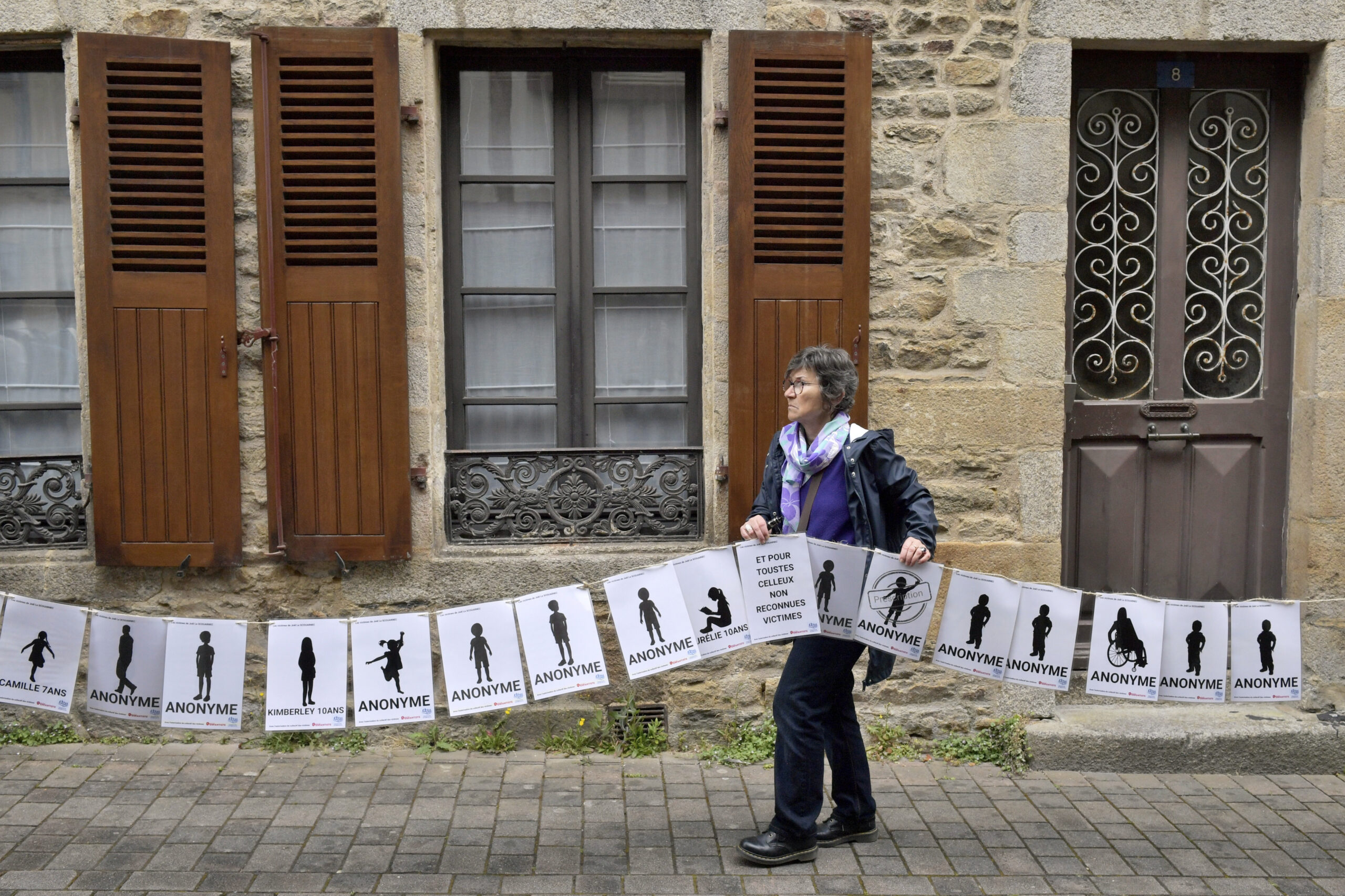 A woman holds a banner representing anonymous victims during a demonstration ahead of the verdict in the trial of Joel Le Scouarnec, a 74-year-old former surgeon, accused of raping and sexually assaulting 299 children, Wednesday, May 28, 2025 in Vannes, Brittany, western France.