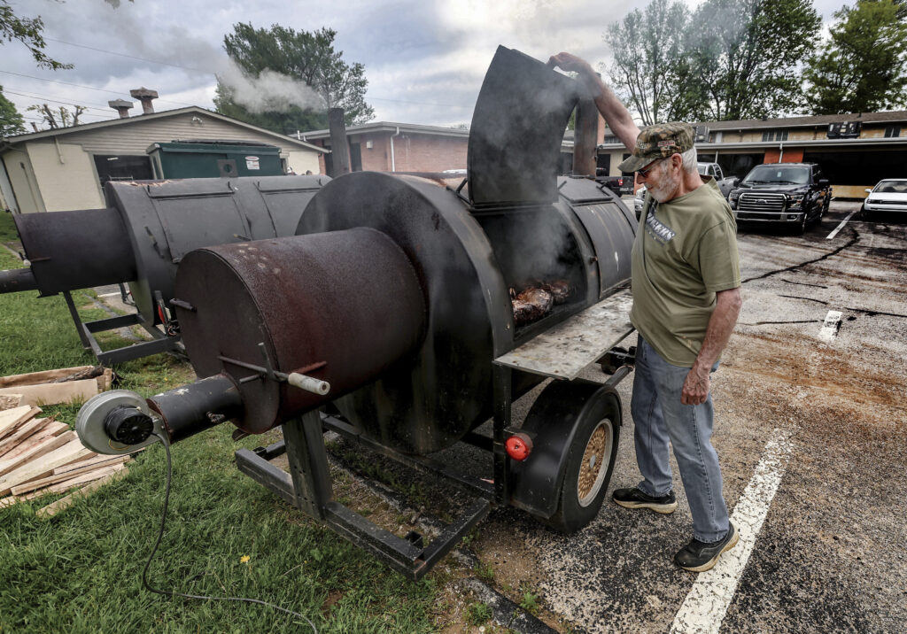 Danny Triplett watches over a smoker filled with Boston butts while working with the cooking team at Precious Blood Catholic Church, Wednesday, May 7, 2025, in Owensboro, Ky.