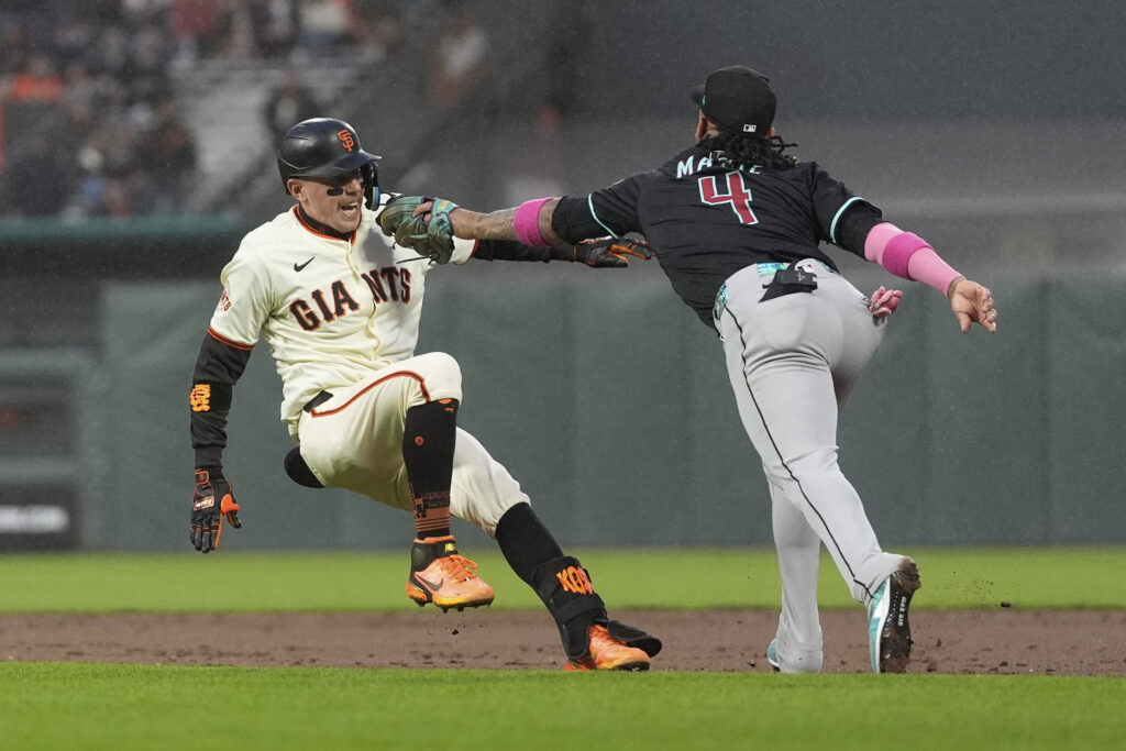 Arizona Diamondbacks second baseman Ketel Marte (4) reaches to tag out San Francisco Giants' Christian Koss after Koss hit an RBI single during the fifth inning of a baseball game in San Francisco, Monday, May 12, 2025.