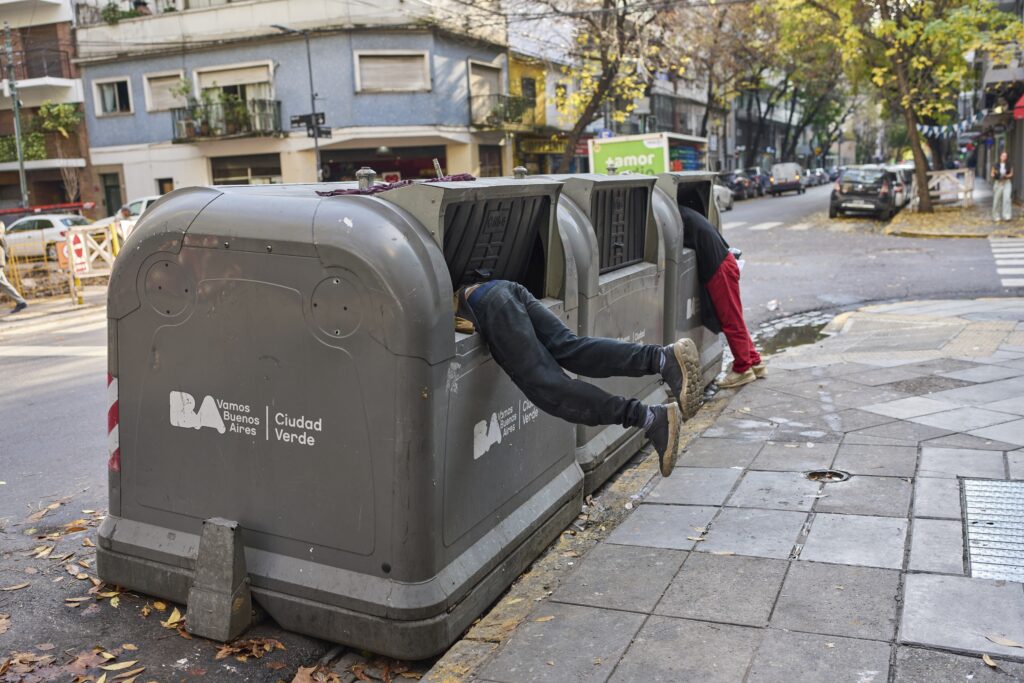 Men search for recyclable items inside public trash cans in Buenos Aires, Argentina, Tuesday, May 6, 2025.