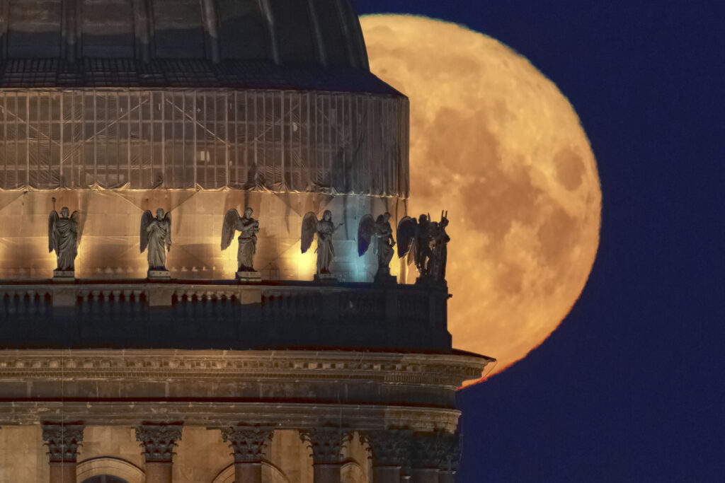 The full moon sets behind the St. Isaac's Cathedral in St. Petersburg, Russia, early Tuesday, May 13, 2025.