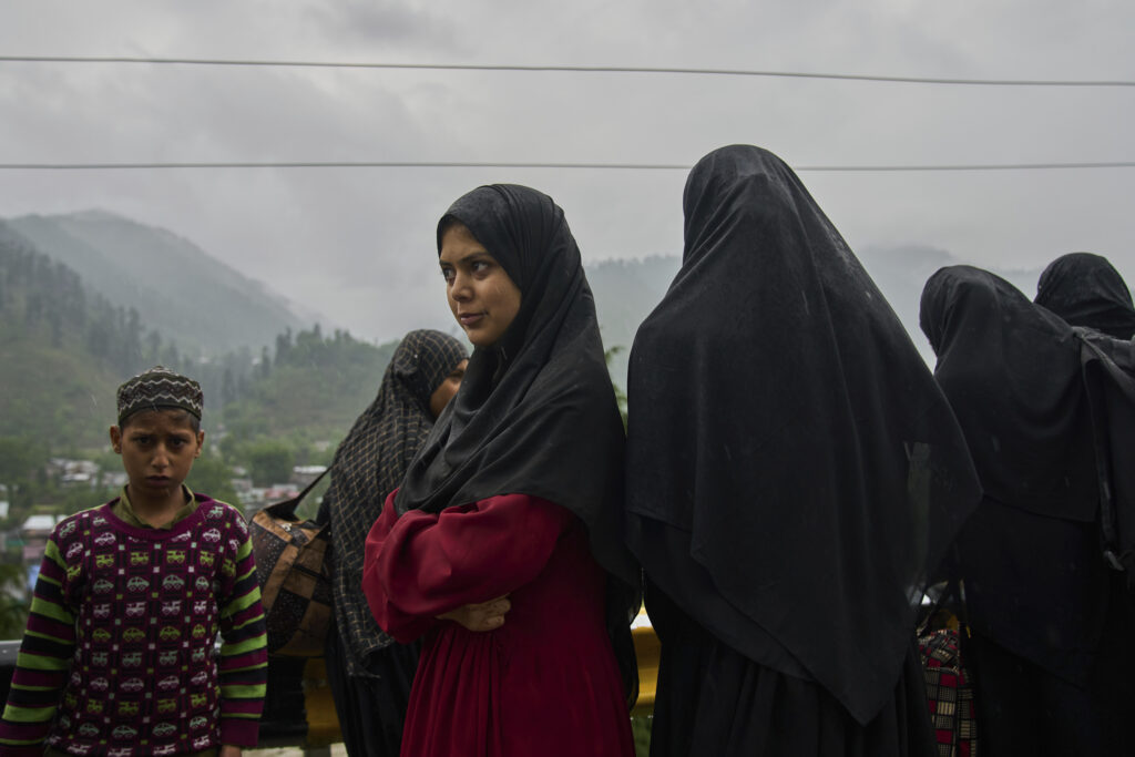 A group of Kashmiri village women wait for transportation as they leave following overnight shelling from Pakistan at Gingal village in Uri, Indian controlled Kashmir, Friday, May 9, 2025.