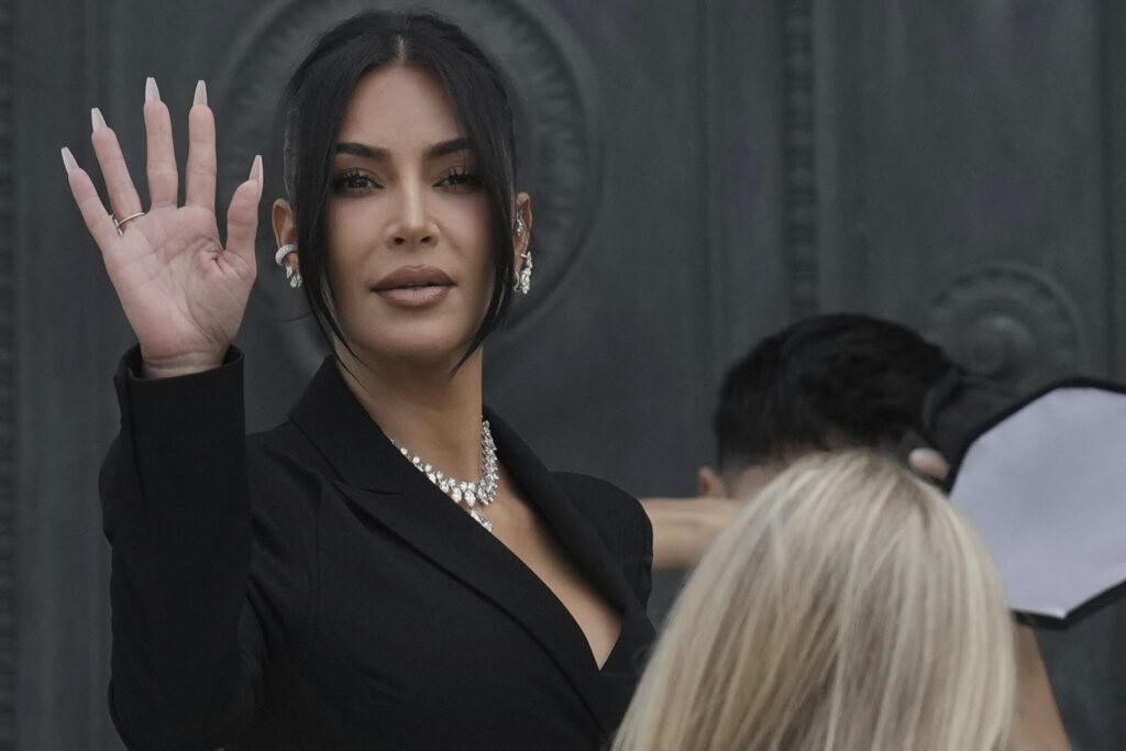 Kim Kardashian waves as she arrives to testify regarding a robbery of millions of dollars in jewels from her Paris hotel room in 2016, in Paris, Tuesday, May 13, 2025.