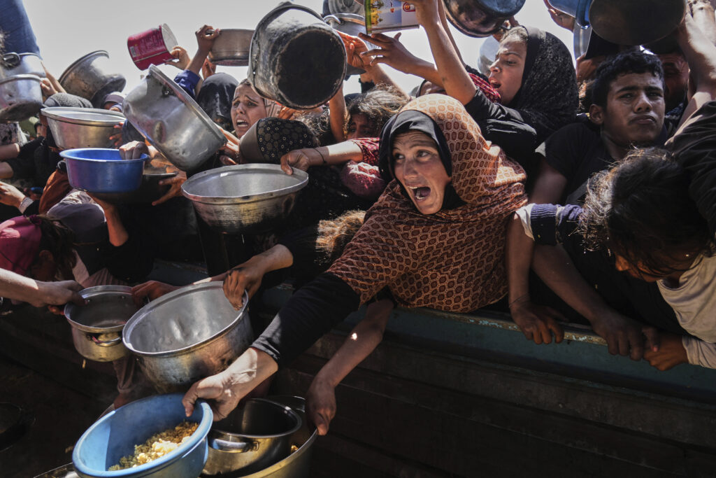 Palestinians struggle to obtain donated food at a community kitchen in Khan Younis, in the southern Gaza Strip, Friday, May 9, 2025.