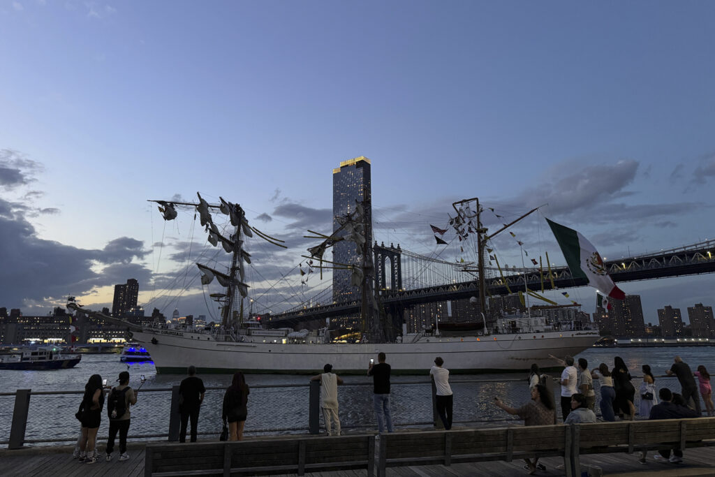 Pedestrians walking along Brooklyn Bridge Park look on as a masted Mexican Navy training ship sits stranded near the Manhattan Bridge after colliding with the Brooklyn Bridge, Saturday, May 17, 2025, in New York. Nick Corso via AP
