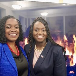 Justice Dweynie Paul (left) and Judge Betsey Jean-Jacques (right) stand in front of a virtual fireplace at the New York County Supreme Court’s Haitian Heritage Fireside Chat, held on May 22 at 60 Centre Street in Manhattan. Photo courtesy of Justice Joanne Quinones