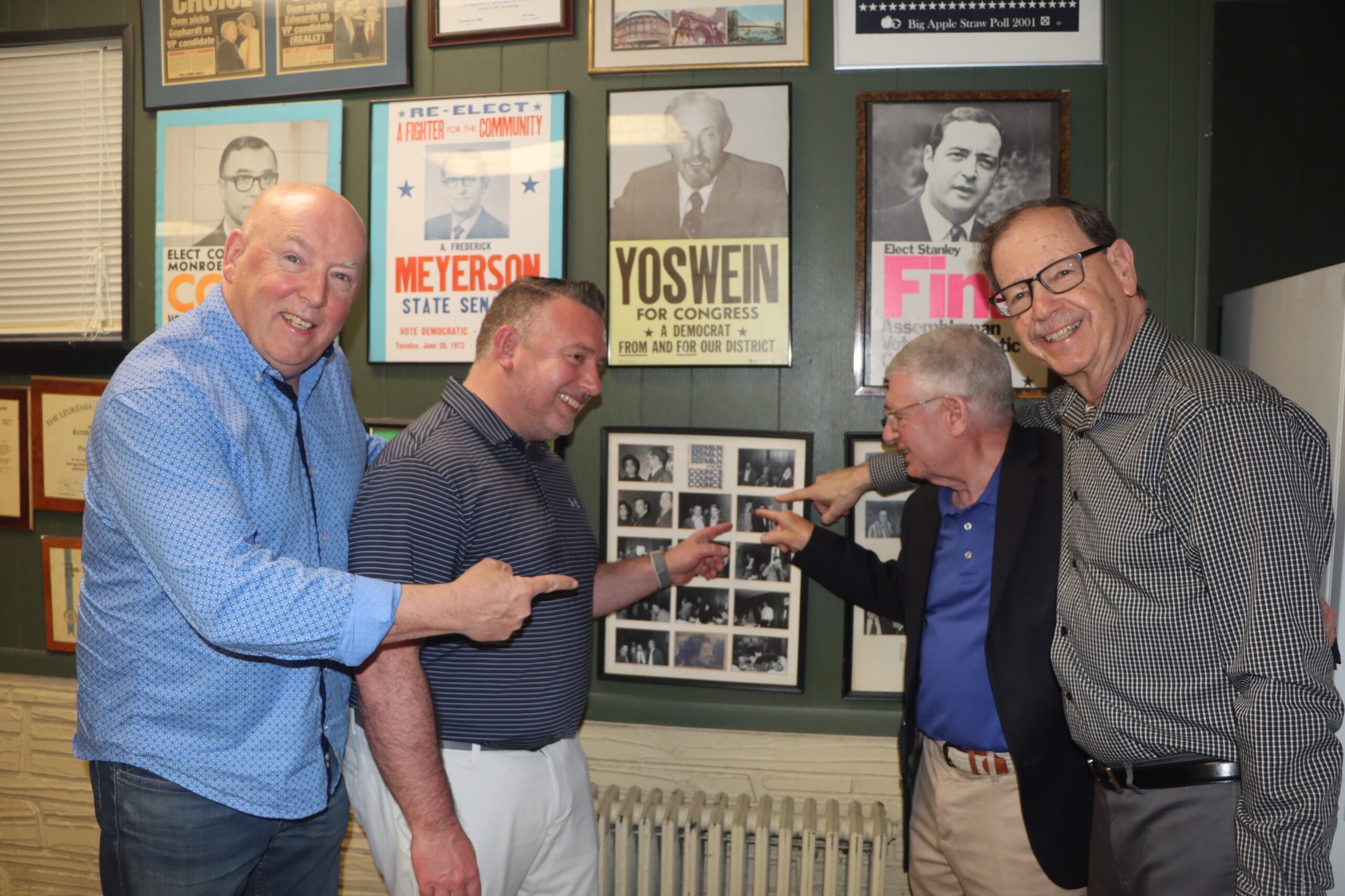 Hon. Mark Partnow (right), Hon. William Mastro and guests point out a photo collage. Photo by Mario Belluomo