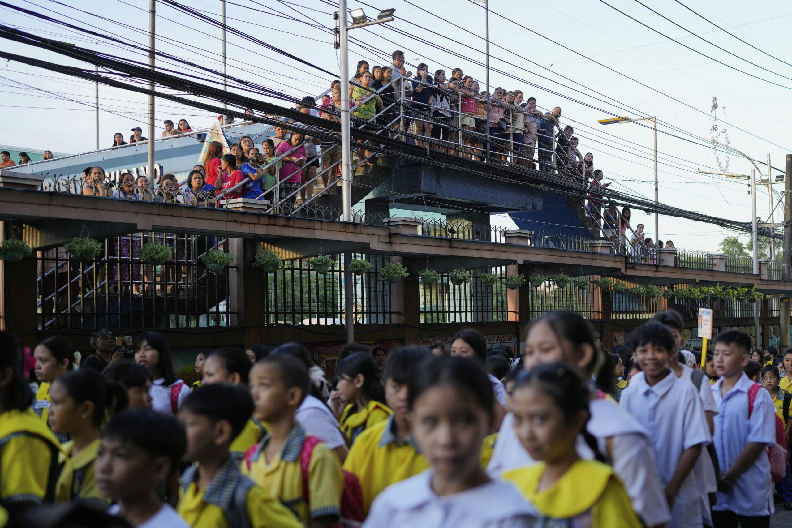 Parents and guardians look from outside the gates of an elementary school during the opening of the new school year in Quezon city, Philippines on Monday, June 16, 2025.