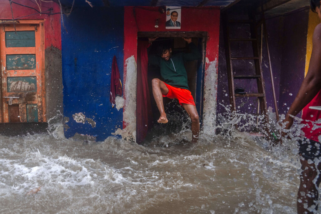 A man jumps as waves lash his house during high tide on the shore of the Arabian Sea in Mumbai, India, Wednesday, June 25, 2025.