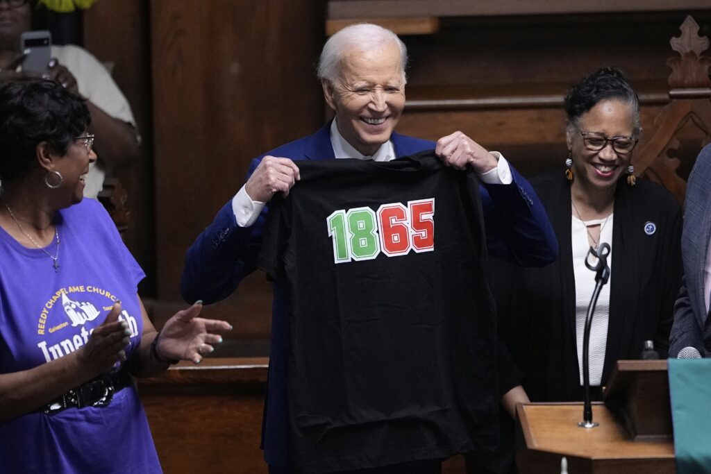 Former President Joe Biden holds up a T-shirt designed with the date 1865 during a Juneteenth event at the Reedy Chapel AME Church, Thursday, June 19, 2025, in Galveston, Texas.