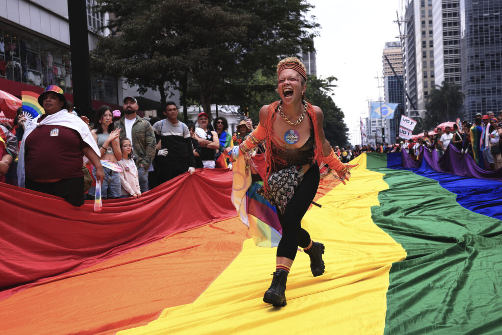 A reveler runs on a large rainbow flag during the annual Pride parade marking LGBTQ+ Pride Month, in Sao Paulo, Sunday, June 22, 2025.