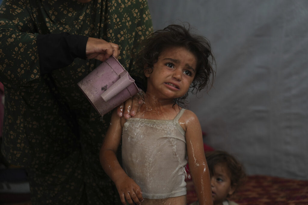 Rida Abu Hadayed, 32, uses water to cool off her 2-year-old daughter Azhar inside their tent at a camp for displaced people in Khan Younis, southern Gaza Strip, Tuesday, July 1, 2025.