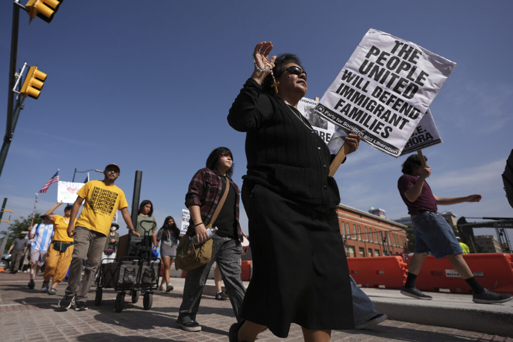 Sister RoseAnn Castilleja, center, holds a Rosary and sign as she marches with other immigration advocates as they protest recent detentions by ICE outside the immigration court in San Antonio, Texas, Tuesday, July 1, 2025.