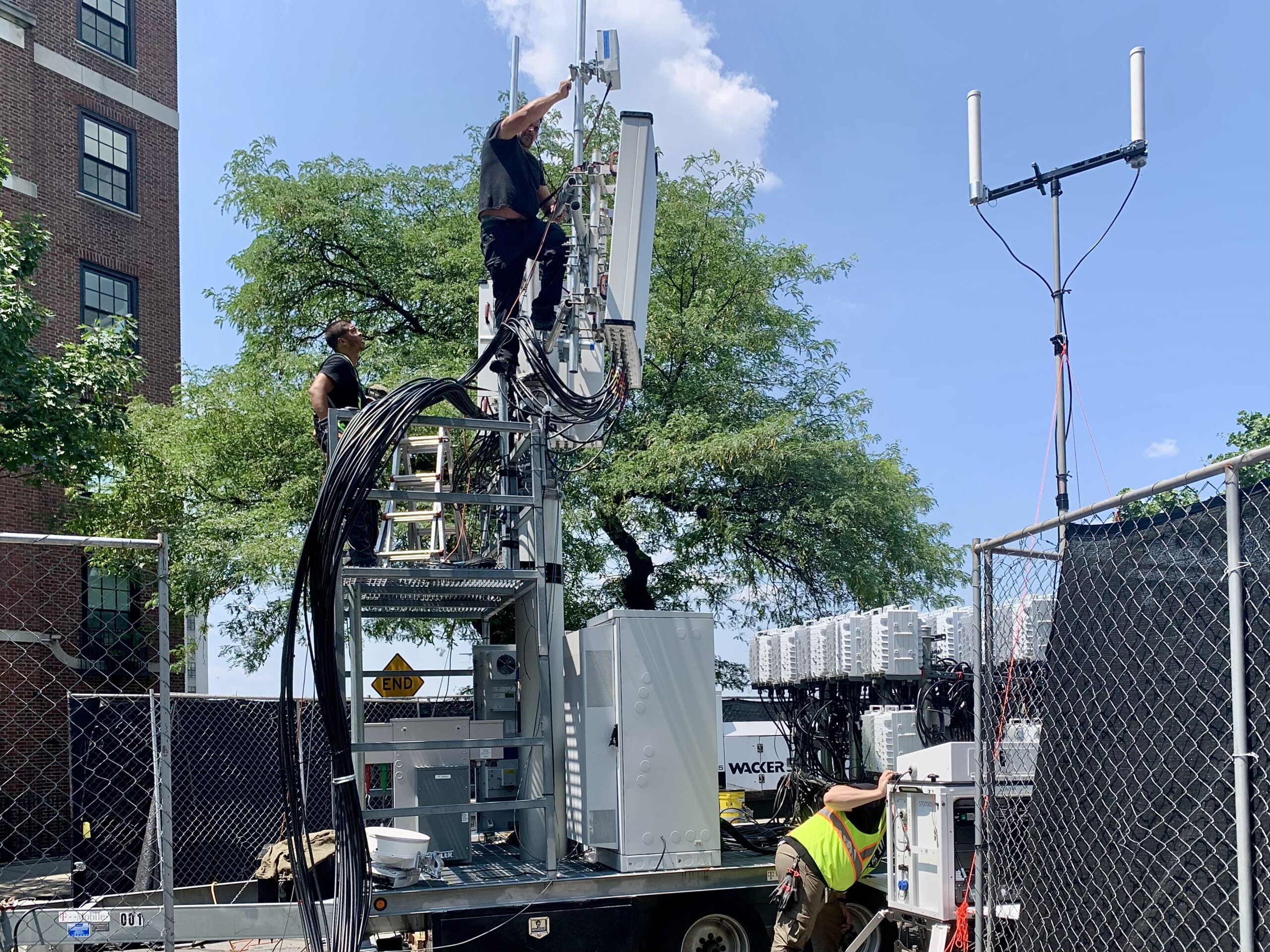 AT&T and T-Mobile technicians install COWs — temporary cell towers — in case 100,000 people start using their phones all at once during the Fourth of July fireworks in Brooklyn Heights. Brooklyn Eagle Photo by Mary Frost