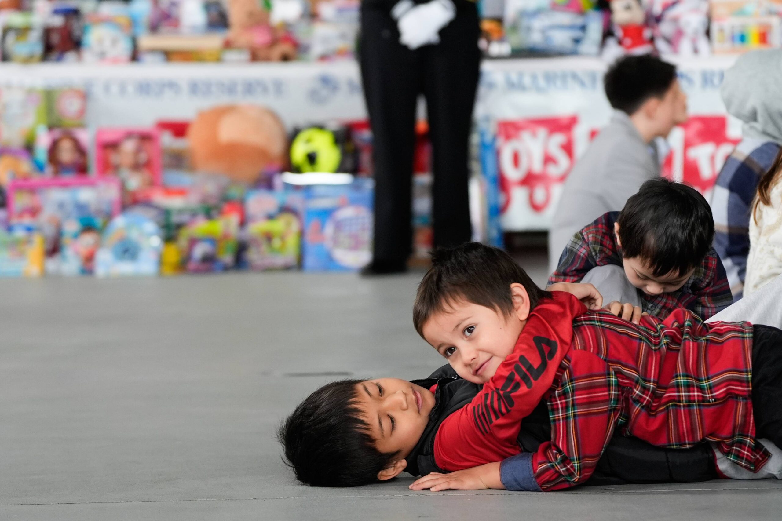 Kids wrestle while first lady Melania Trump speaks during a Toys for Tots charity drive event at Marine Corps Base Quantico, Monday, Dec. 8, 2025, in Quantico, Va. Photo: Julia Demaree Nikhinson/AP
