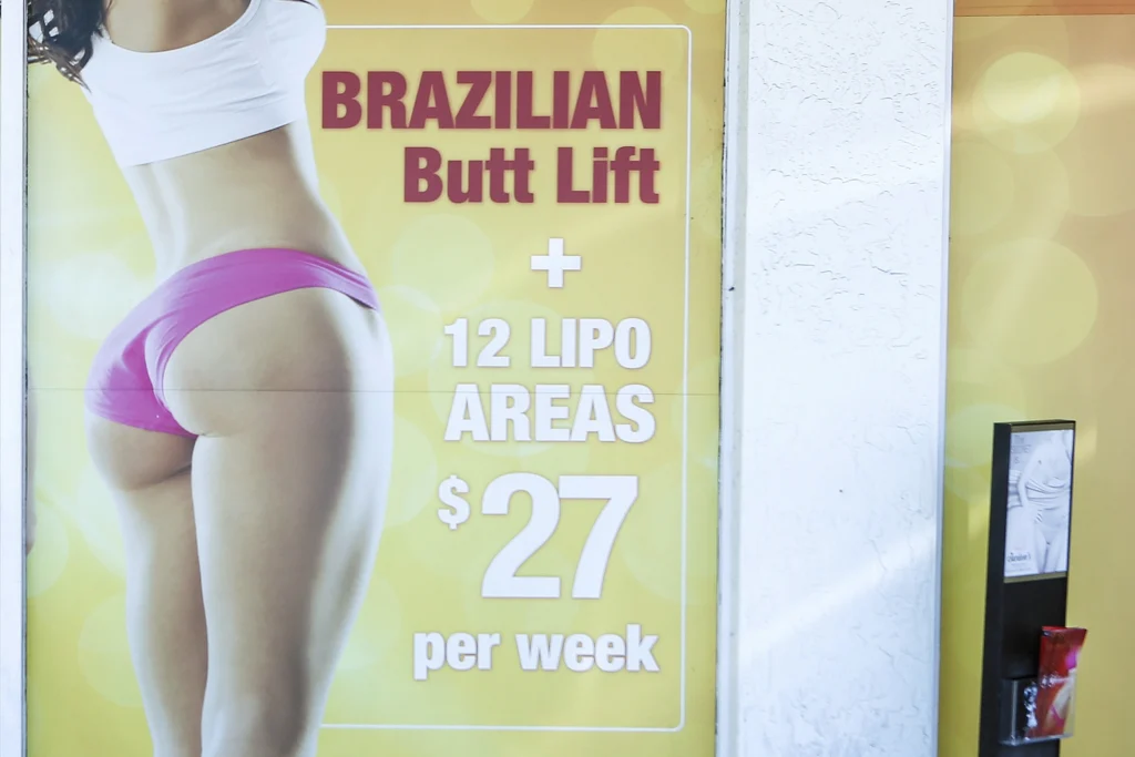 A window display advertises low-cost "Brazilian butt lift" cosmetic surgery procedures outside a clinic in Miami on Friday, March 22, 2019. On Thursday, Jan. 25, 2024, the Centers for Disease Control and Prevention said 93 Americans have died after cosmetic surgery in the Dominican Republic since 2009, with many of the recent deaths involving a procedure known as a Brazilian butt lift. Photo: Ellis Rua/AP