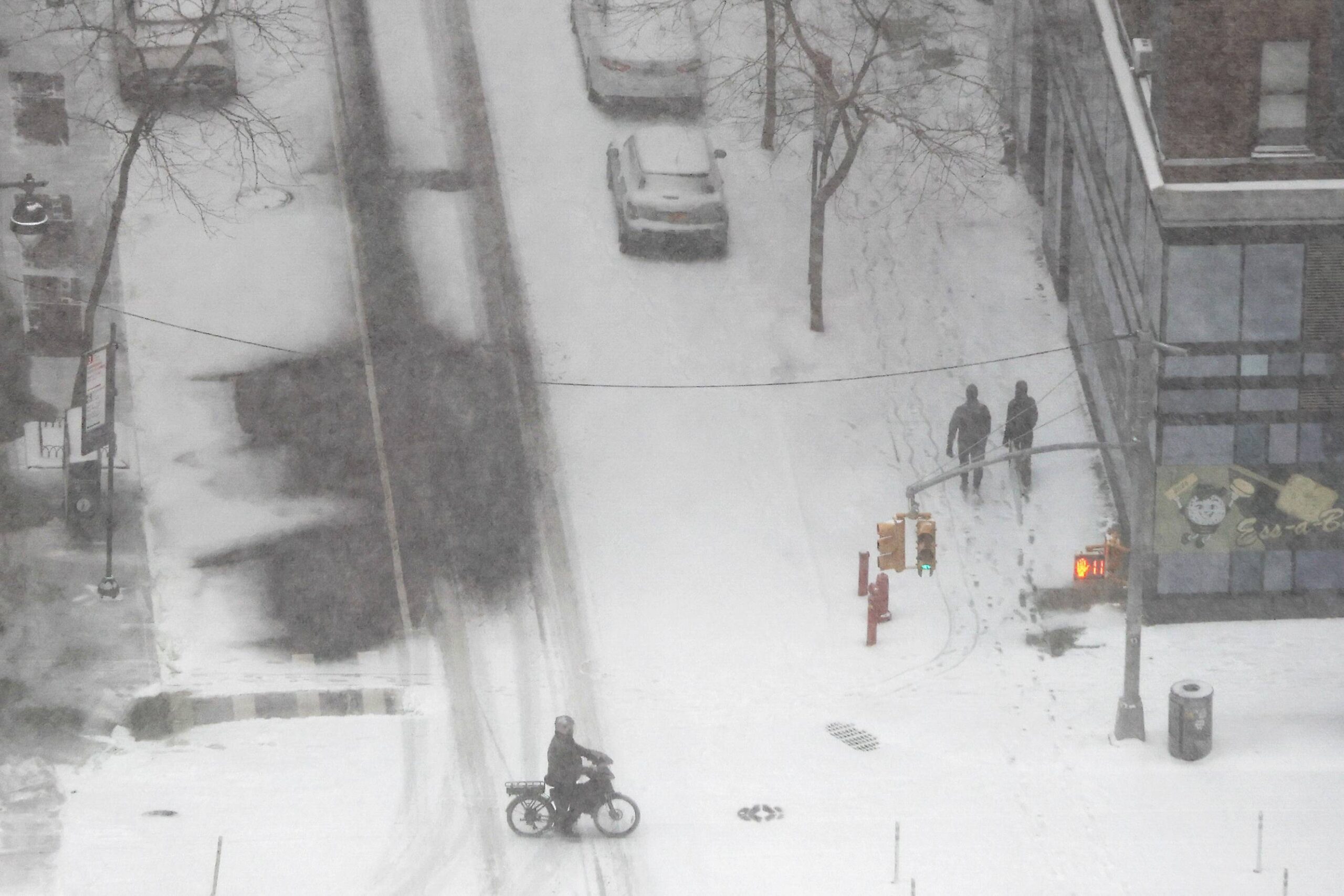 Pedestrians walk and ride their bike as heavy snow falls, Sunday, Jan. 25, 2026, in New York. Photo: Heather Khalifa/AP