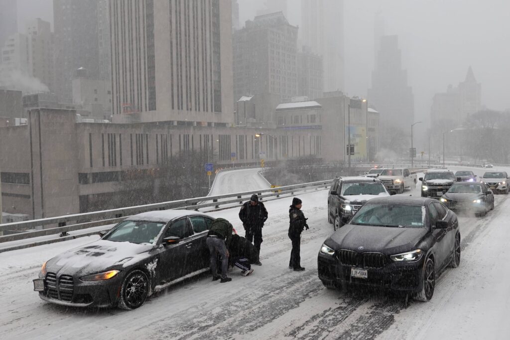 Police direct traffic past a car stuck going across the Brooklyn Bridge as it snows on Sunday, Jan. 25, 2026, in New York. Photo: Alyssa Goodman/AP