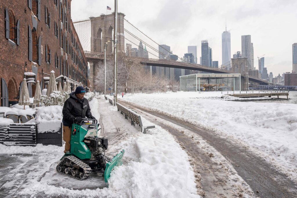 A worker clears snow outside the Empire Stores building in Brooklyn Bridge Park, Wednesday, Feb. 25, 2026, in the Brooklyn borough of New York. Photo: Yuki Iwamura/AP