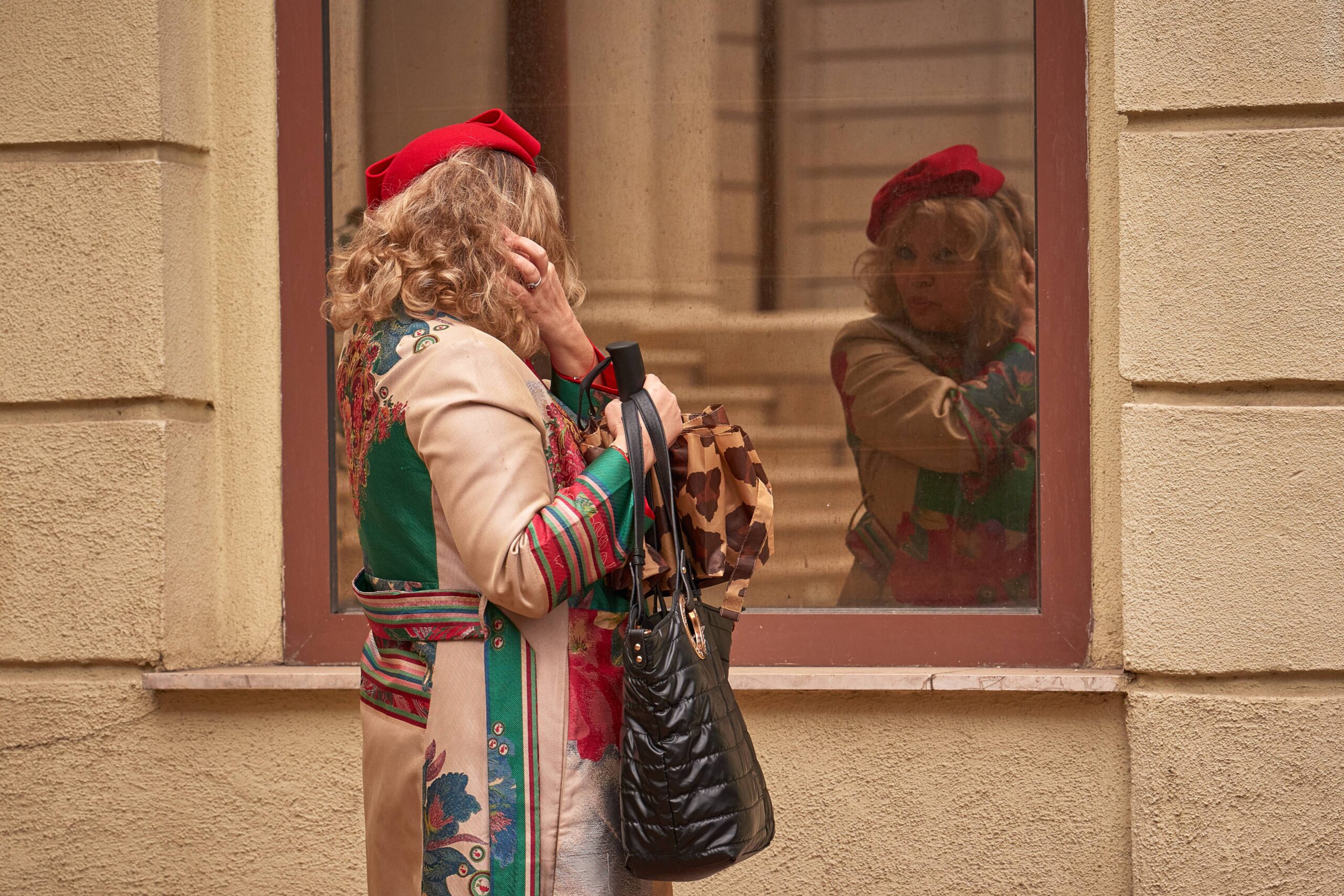 A participant in the World Hat Walk, an event which, according to organizers, takes place in up to 60 cities across the world, promoting headwear, checks her outfit in a window n Bucharest, Romania, Sunday, May 10, 2026. Photo: Vadim Ghirda/AP