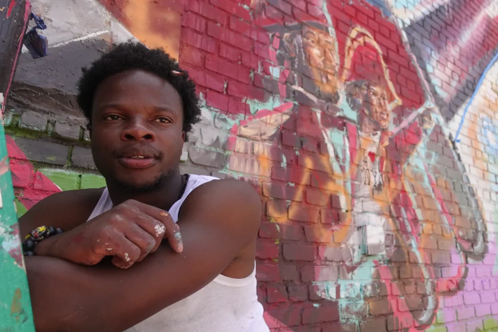 Haitian immigrant and former TPS holder Doudgy Charmant was painting a mural in Brooklyn’s Little Haiti honoring the island’s history when the Supreme Court’s ruling on temporary protective status was issued, June 25, 2026. Credit: Gwynne Hogan/The City Reporter