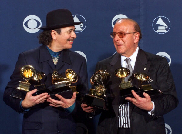 FILE - Carlos Santana, left, and producer Clive Davis pose with their Grammys at the 42nd Grammy Awards in Los Angeles, on Feb. 23, 2000. (AP Photo/Reed Saxon, File)